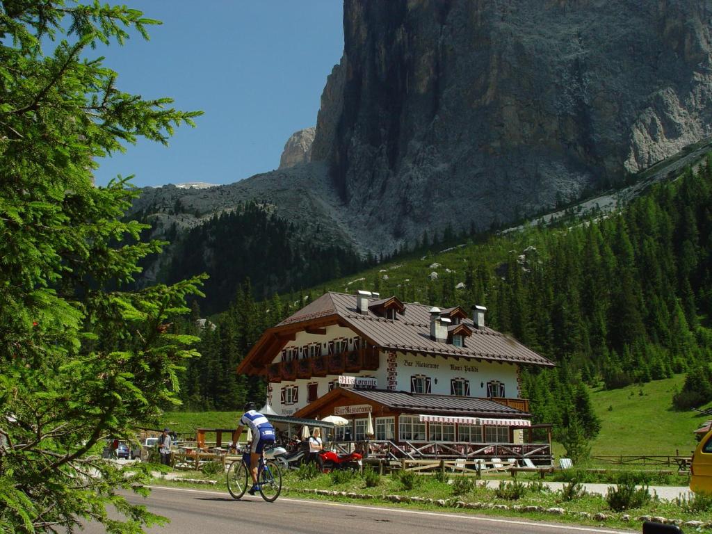 Ein Mann, der vor einem Gebäude Fahrrad fährt in der Unterkunft Rifugio Monti Pallidi in Canazei