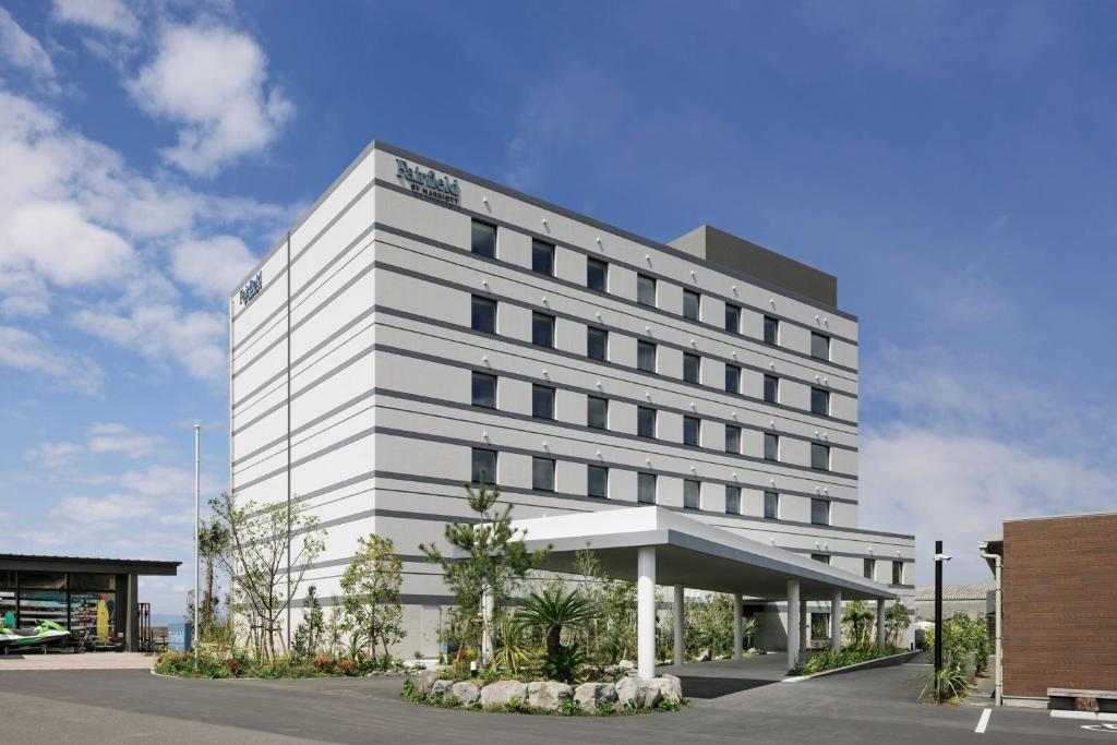 un edificio bianco con un parcheggio di fronte di Fairfield by Marriott Kagoshima Sakurajima a Tarumizu