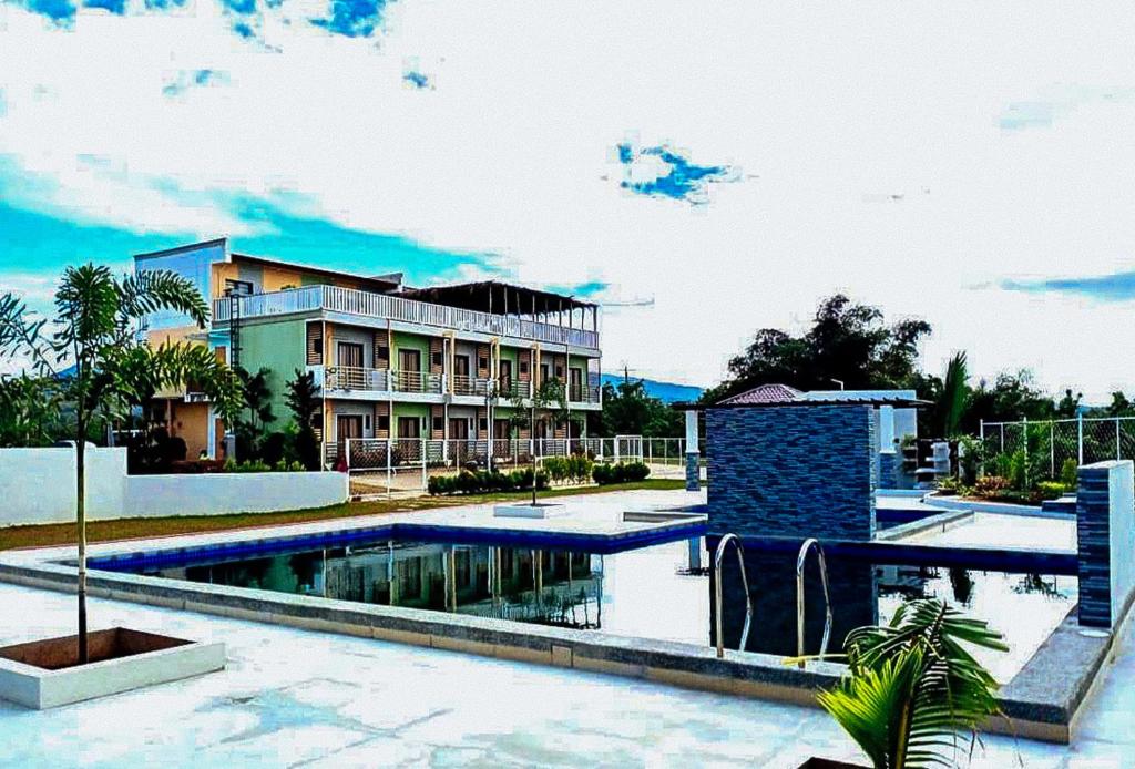 a resort with a swimming pool in front of a building at Jeanine's Travellers Inn by RedDoorz in Morong