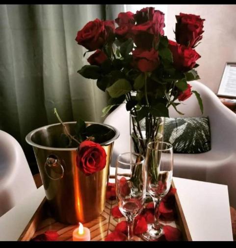 une table avec un vase avec des roses et deux verres à vin dans l'établissement Appartement jacuzzi privatif Love&Zen, à Verneuil-sur-Avre