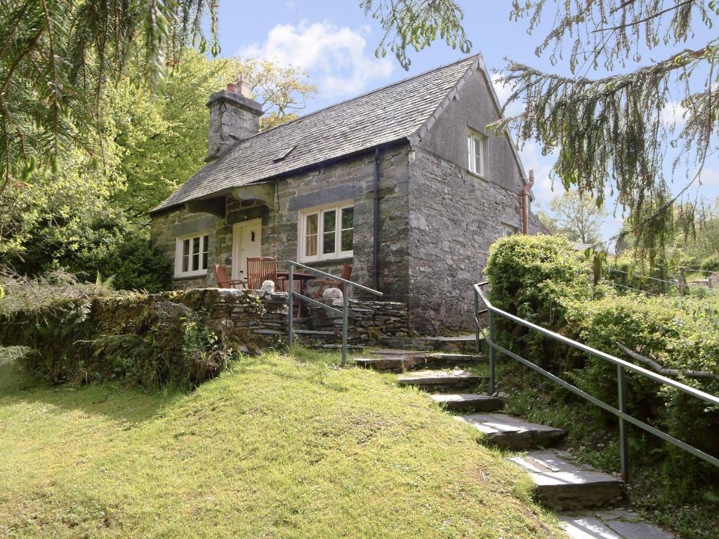 an old stone house with stairs in front of it at Dylasau Cottage in Capel Garmon