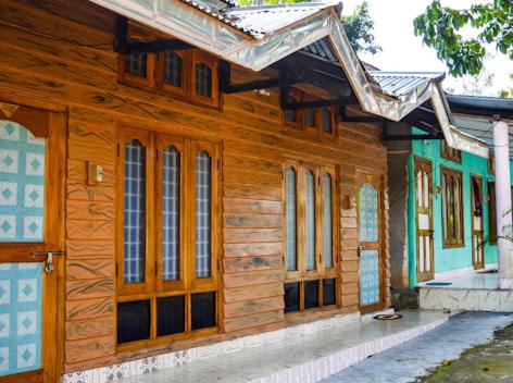 a wooden house with wooden doors and windows at Green Reed Resort By Meenakshi, Kaziranga in Hatikhuli