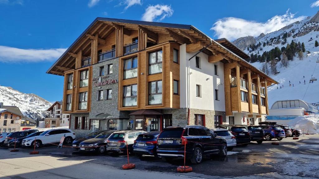 a large building with cars parked in a parking lot at Hotel Gamsleiten in Obertauern