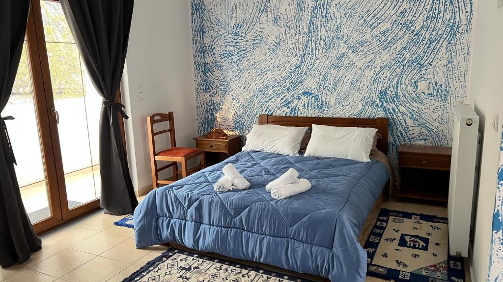 a bedroom with a blue bed with towels on it at Kanalis Houses in Avlonárion