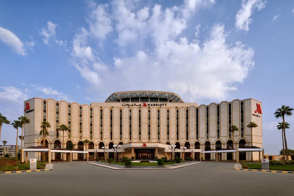 Riyadh Airport Marriott Hotel في الرياض: مبنى كبير أمامه أشجار نخيل