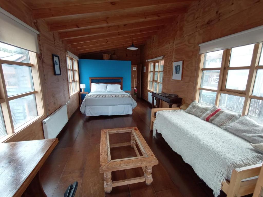 a bedroom with a bed and a couch and windows at Hostal Palafito Waiwen in Castro