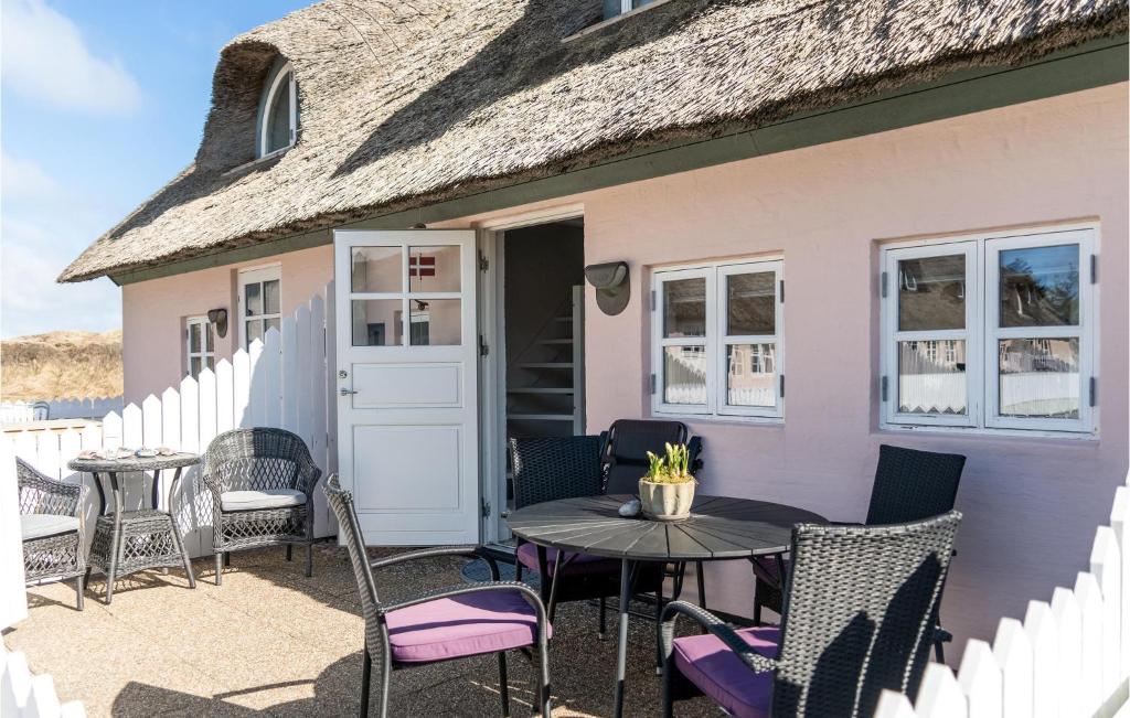 a patio with chairs and a table in front of a pink house at Stunning Home In lbk With Wifi in Ålbæk