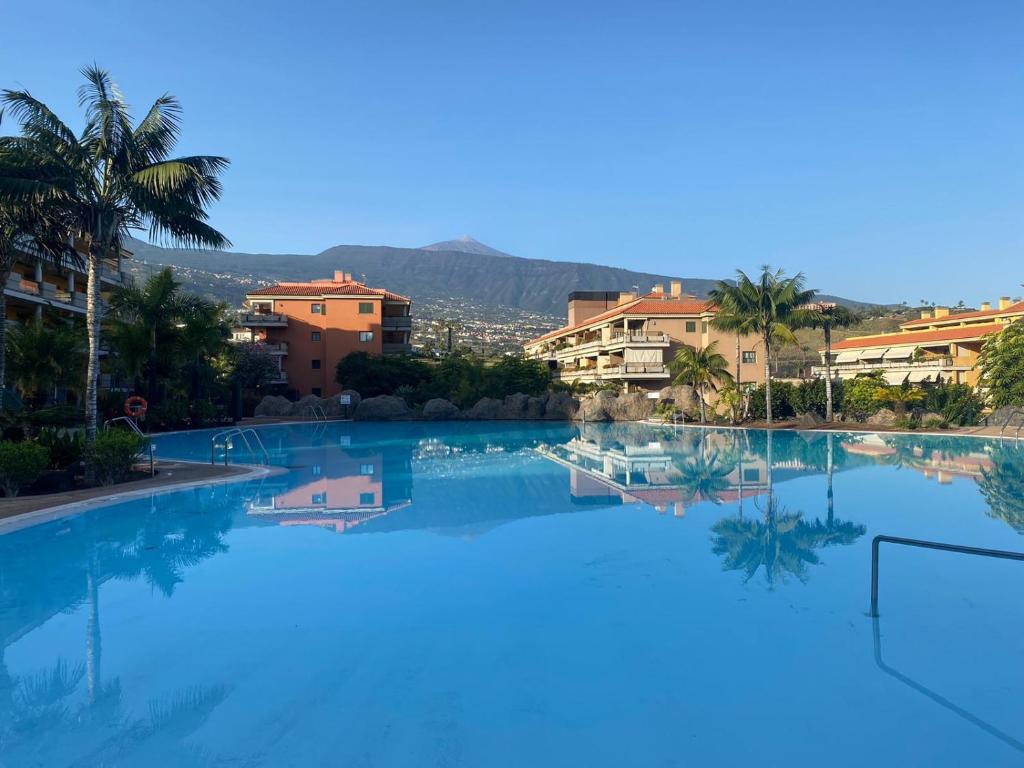 ein großer Swimmingpool mit Palmen und Gebäuden in der Unterkunft RESIDENCIAL JARDINES DEL TEIDE, 126 in Puerto de la Cruz