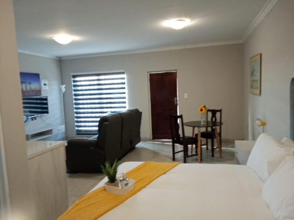 um quarto de hotel com uma cama, uma mesa e cadeiras em Bella's self contained daily accommodation em Meyerton