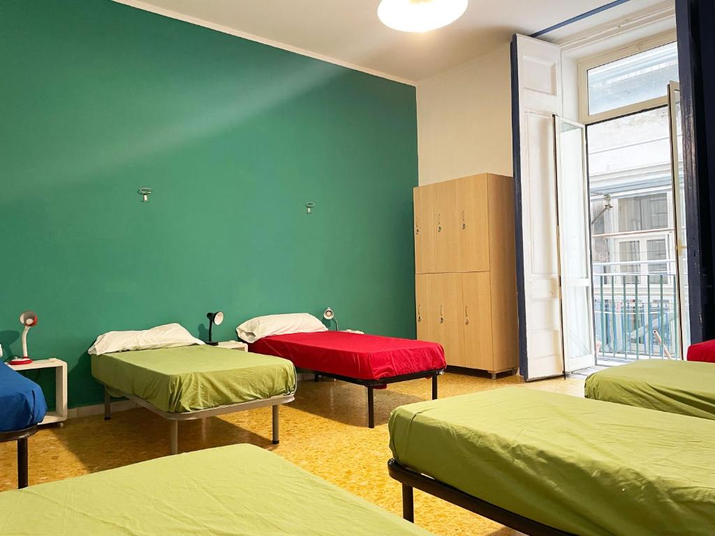 ナポリにある6 Small Roomsのベッド3台と窓が備わる客室です。