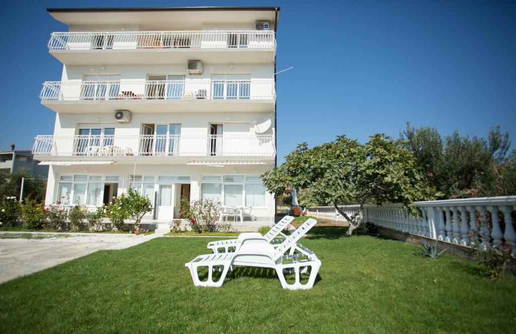 Deux chaises blanches assises sur l'herbe devant un bâtiment dans l'établissement Beach Studio Apartment Ivana, à Kaštela