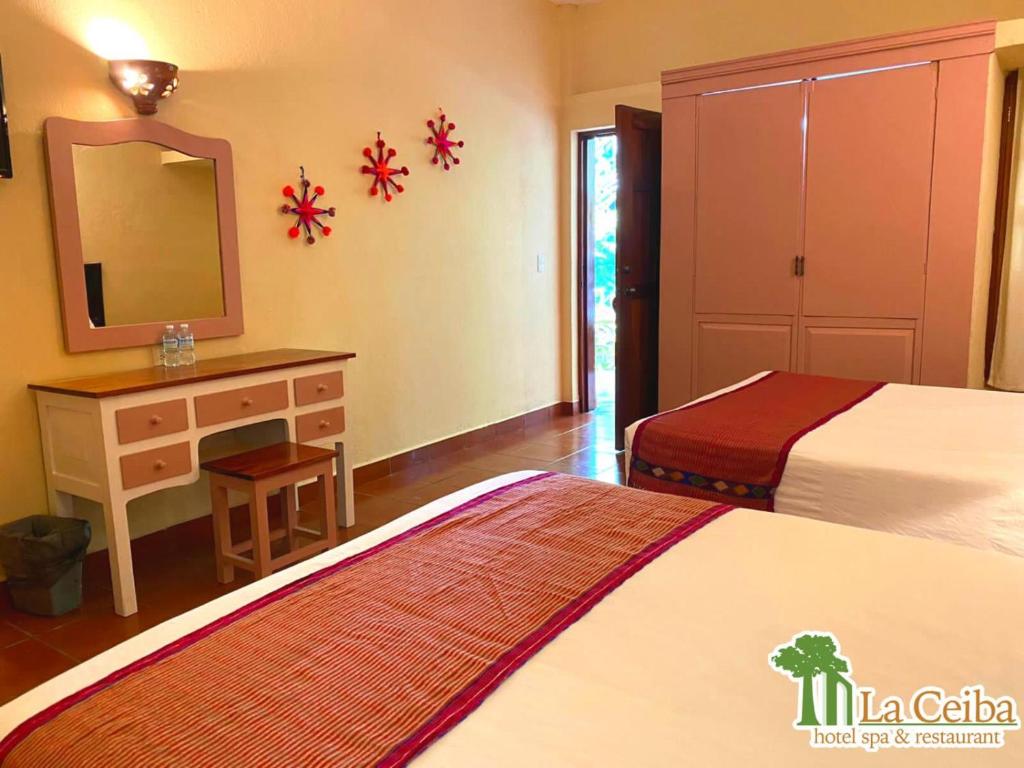 a bedroom with two beds and a dresser and a mirror at Hotel La Ceiba in Chiapa de Corzo