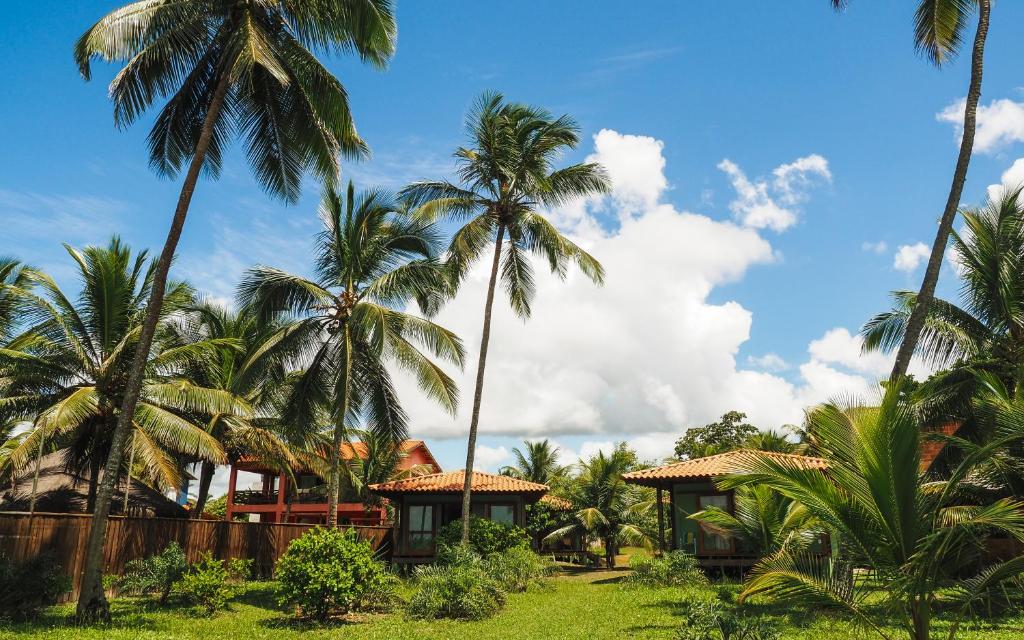 a resort with palm trees in the foreground at Manawa Bangalôs in Serra Grande