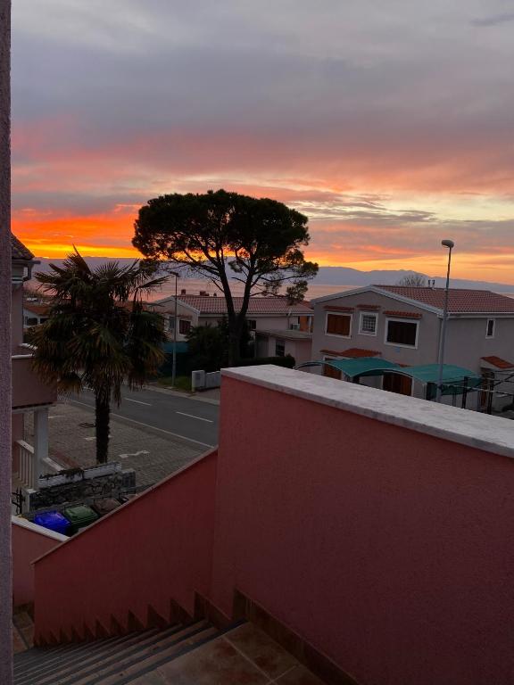 a sunset from the balcony of a building with a tree at Apartmani HILA in Njivice