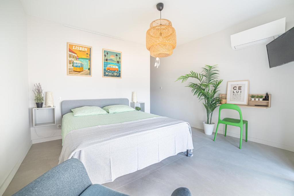 a white bedroom with a bed and a green chair at CASA LC chambre2 vue Mer Jacuzzi in Ajaccio