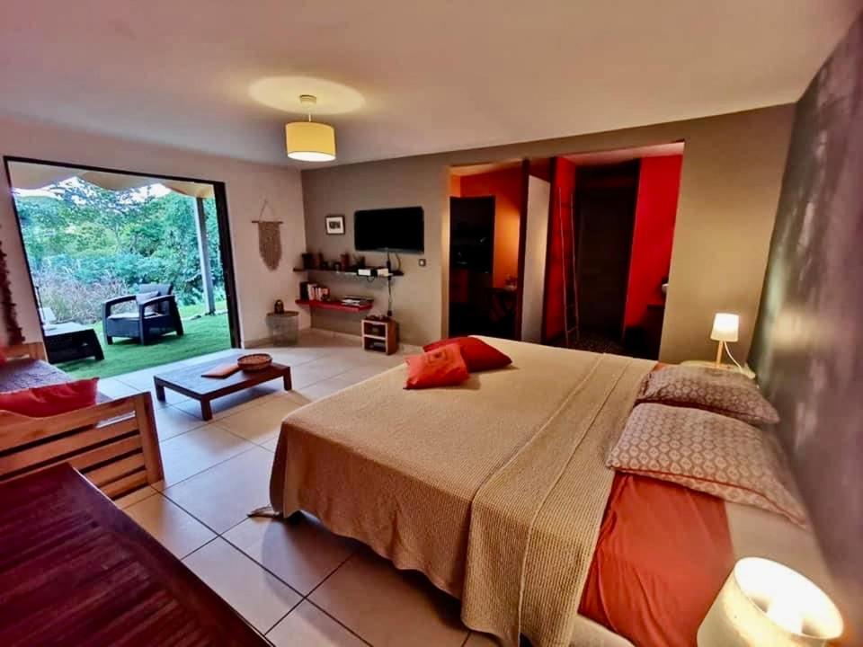 a bedroom with a large bed and a living room at Aluna Ecolodge in Petit-Bourg