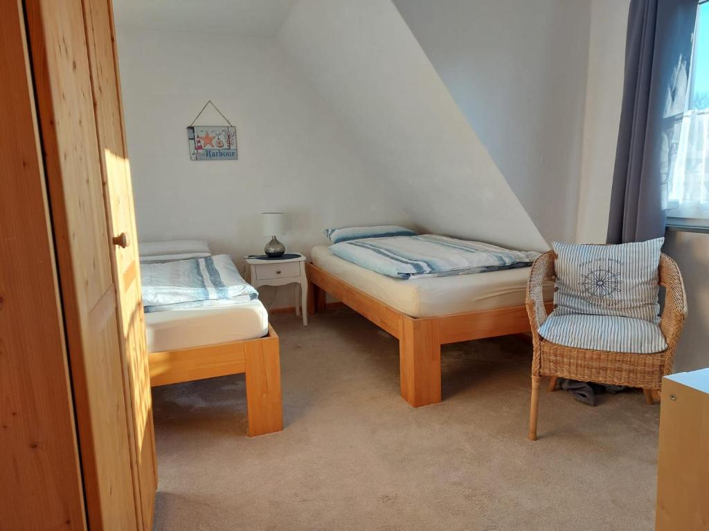 a bedroom with two twin beds and a chair at Voslapper Seeluft in Wilhelmshaven