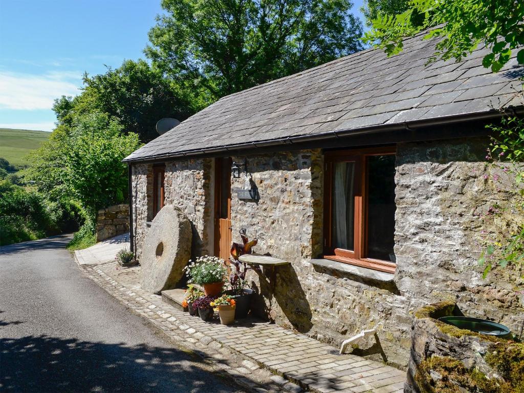 a stone house with a window and a road at The Smithy in Brentor