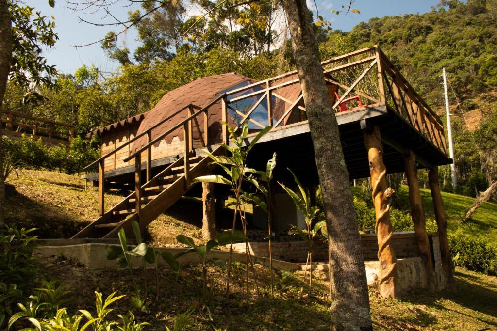 a building with a roof and stairs next to a tree at FINCA CELESTIAL in Pacho