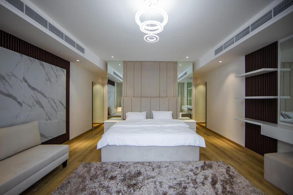 een slaapkamer met een groot wit bed en een bank bij Jeema lodge in Hatta