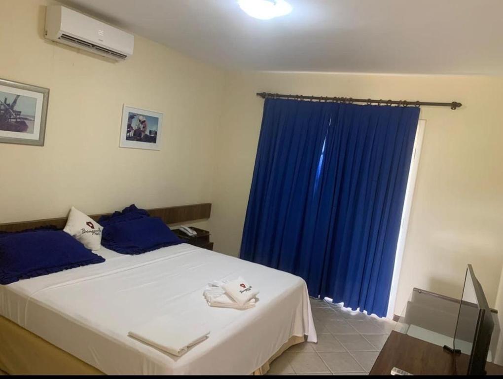 a bedroom with a large bed with a blue curtain at Bouganville Hotel in Beberibe