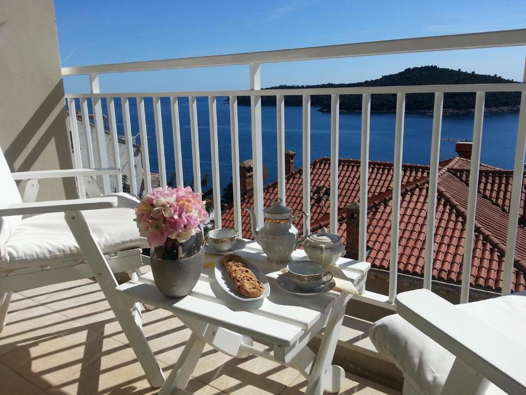 una mesa con comida y flores en el balcón en Dubrovnik Residence Nodilo, en Dubrovnik