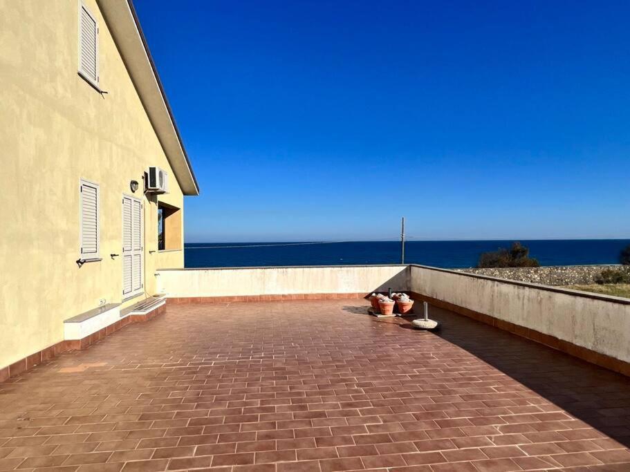 une passerelle en briques à côté d'un bâtiment au bord de l'océan dans l'établissement Casa vicino al mare, à Bianco
