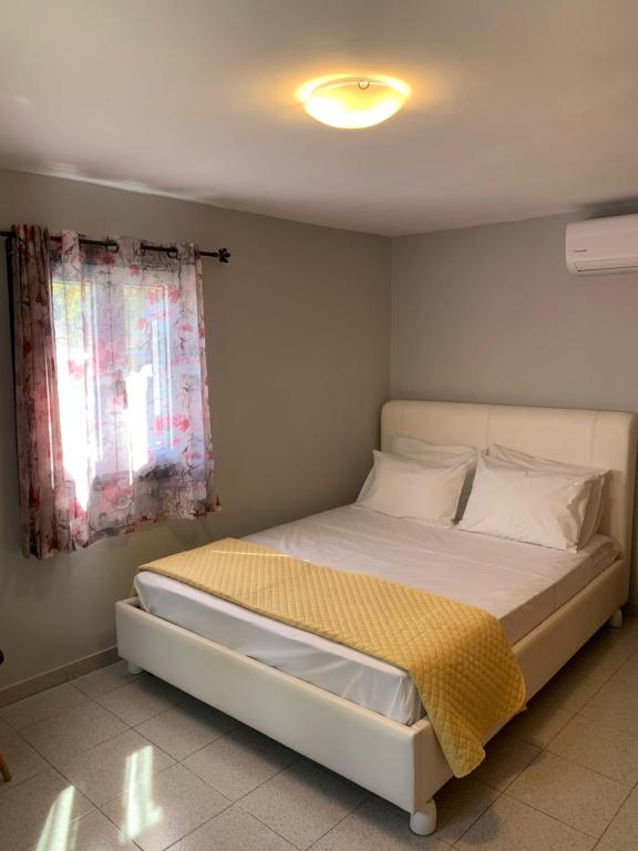 um quarto com uma cama branca e uma janela em Lofos house em Karavádhos