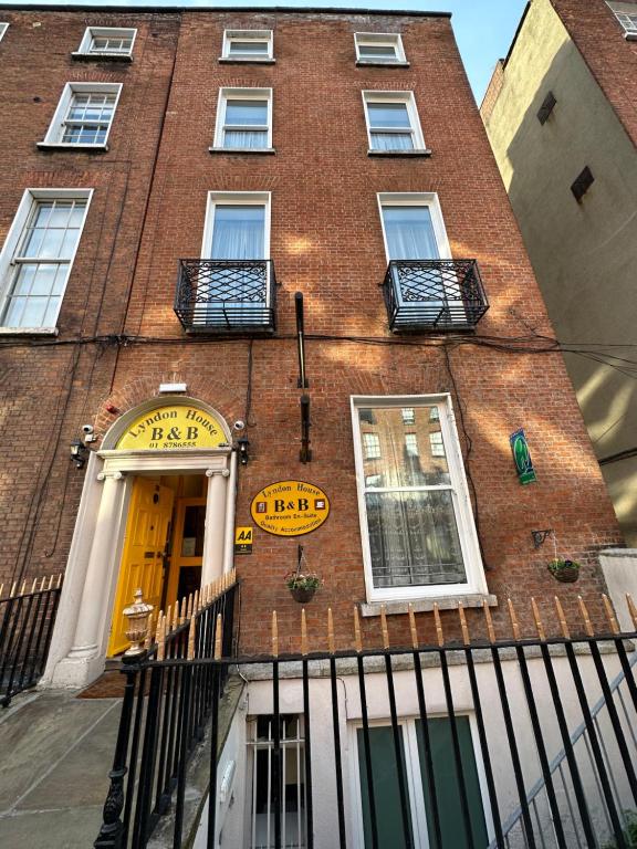 een hoog bakstenen gebouw met een gele deur en ramen bij Lyndon Guesthouse in Dublin