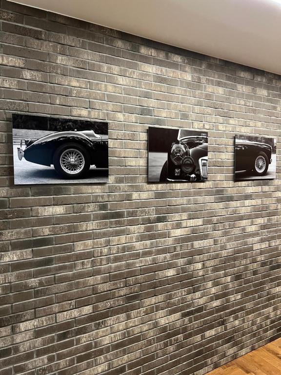 een bakstenen muur met drie foto's van een auto erop bij 101 Large Space in Kaunas