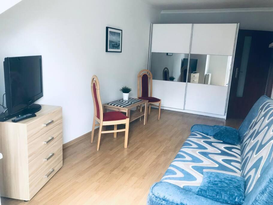 een woonkamer met een bank, een tv en een tafel bij Apartament Kilińskiego w centrum Ustki in Ustka