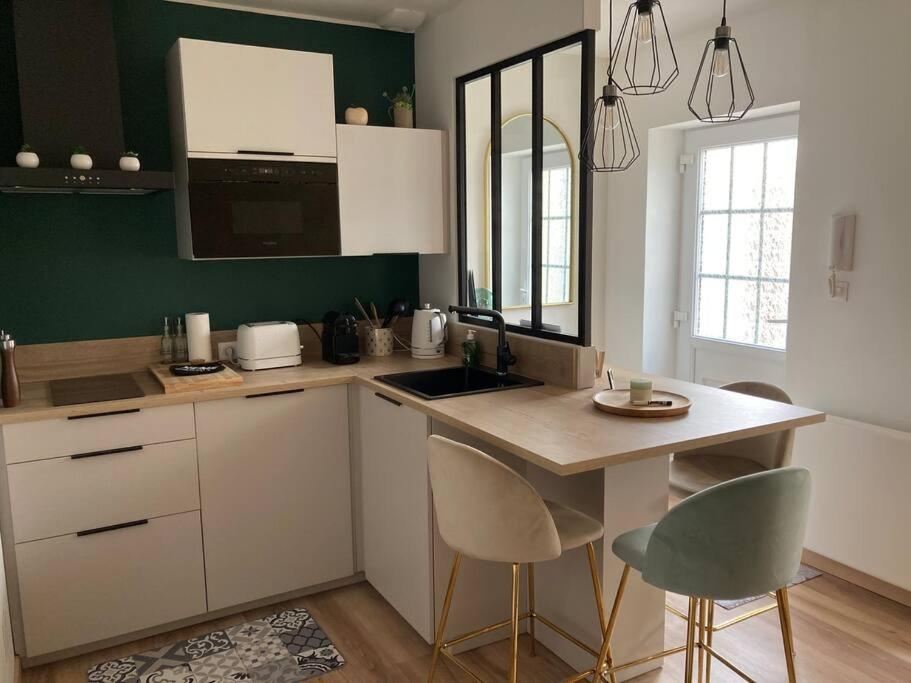 a kitchen with white cabinets and a counter with chairs at LE SAINT CYP - Toulouse - appart entier cosy et au calme, proche du métro in Toulouse