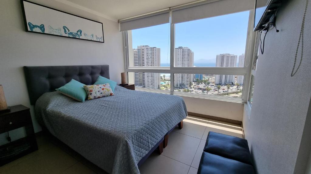 a bedroom with a bed and a large window at Departamento Marina Horizonte II in Coquimbo