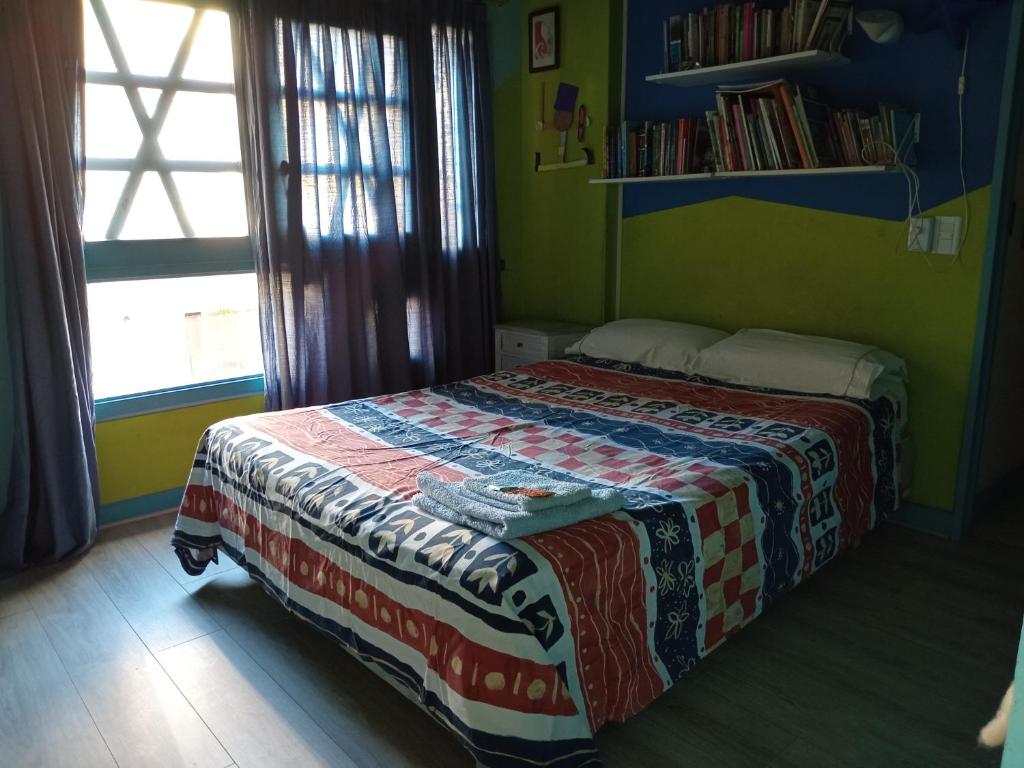 1 dormitorio con 1 cama con edredón en Cuartos en el segundo piso de casa de artista en Flores en Buenos Aires