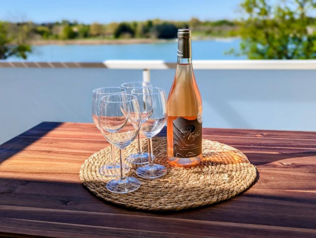 Una botella de vino y dos copas en una mesa. en Lakeside Provence - Appartement 4 étoiles face au lac de Monteux, en Monteux