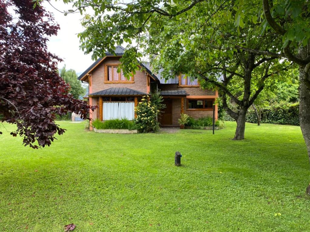 Una casa en un césped verde con una boca de incendios en Lo de Andre, en Lago Puelo