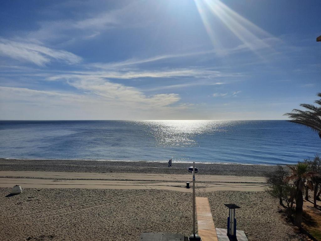 サン・ルイス・デ・サビニリャスにあるPrimera linea de Playa a 10 min Esteponaの水面に太陽が輝く海岸