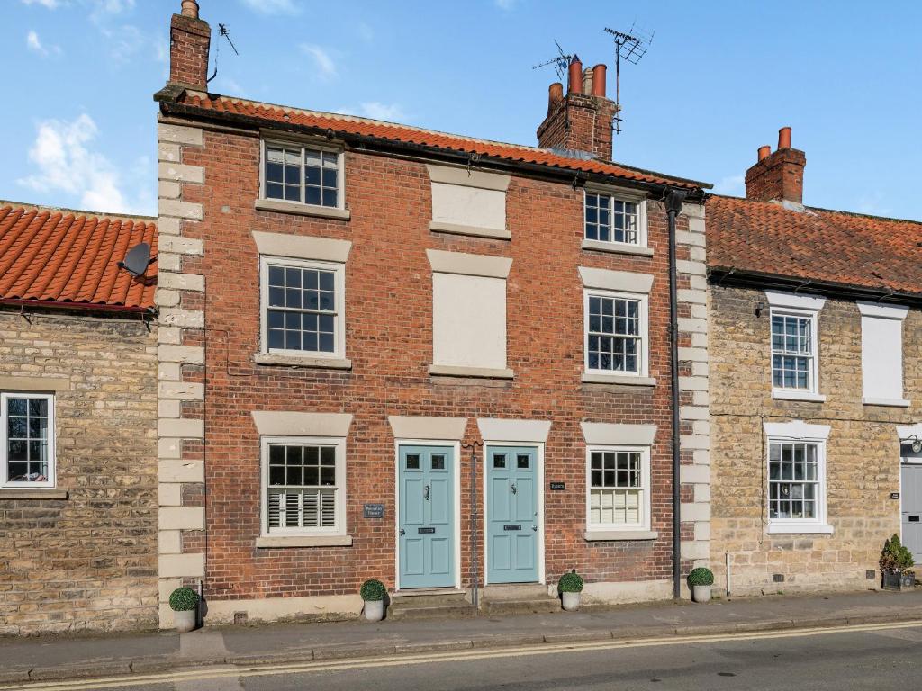 a brick building with blue doors on a street at Beverley House - Uk43519 in Thornton Dale