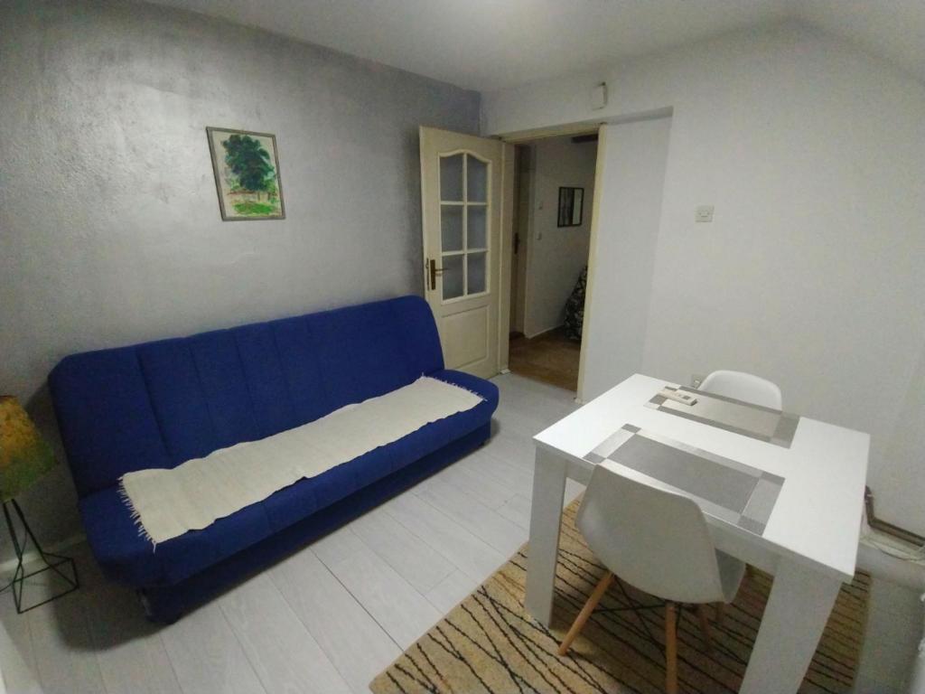 ein Wohnzimmer mit einem blauen Sofa und einem Tisch in der Unterkunft Apartman DM in Valjevo