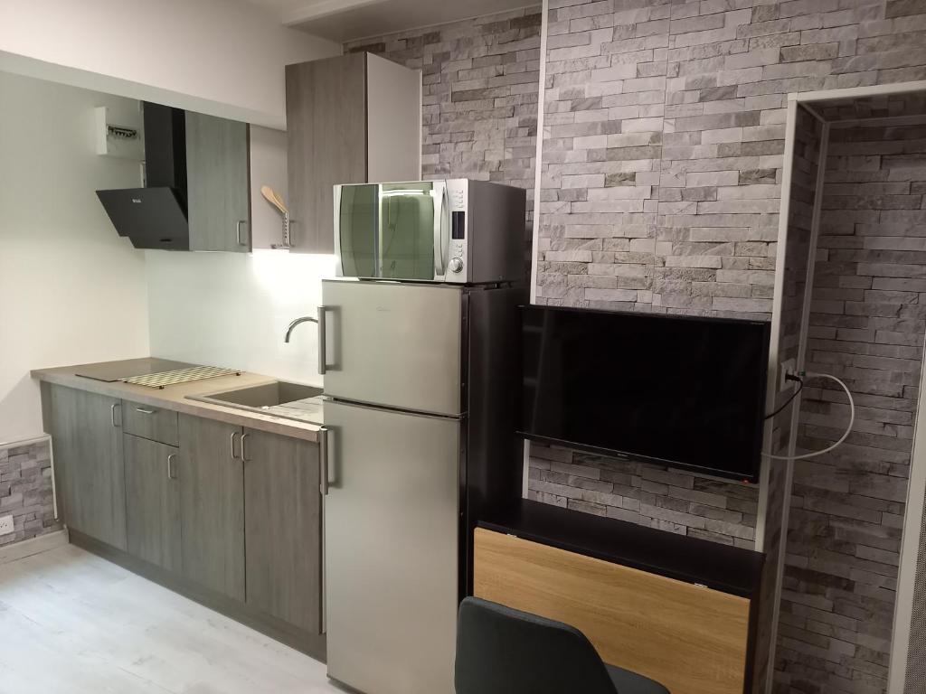 uma cozinha com um frigorífico e uma parede de tijolos em Charmant Studio Centre de Foix 2ème étage em Foix