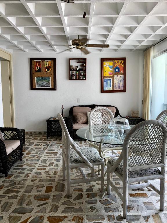 a living room with a table and chairs and a couch at Departamento sobre Costera, 1min La Quebrada, 3m playas y yates in Acapulco