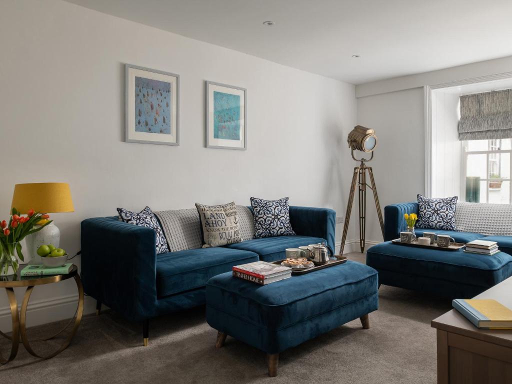 una sala de estar con sofás azules y una mesa. en Tides Door, Fairfax Place, en Dartmouth