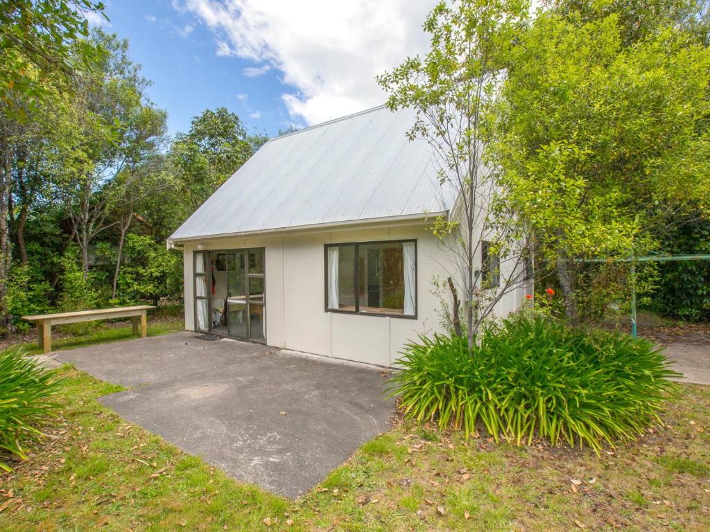 une petite maison blanche avec un banc devant elle dans l'établissement Pihanga Cottage - Kuratau Bach, à Kuratau