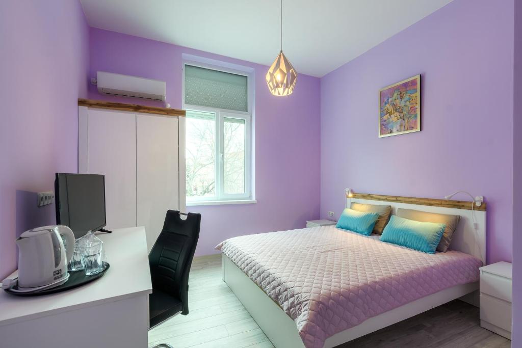 a purple bedroom with a bed and a desk at ПАЦО in Burgas