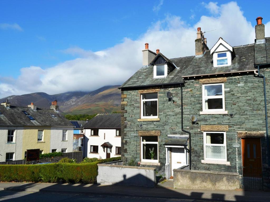 una vecchia casa in pietra con montagne sullo sfondo di Catbells Cottage keswick a Keswick