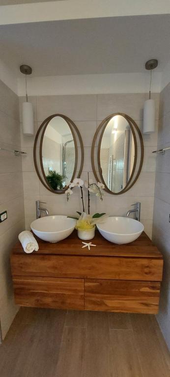 a bathroom with two sinks and two mirrors at Sweet Home Simona in Zambrone
