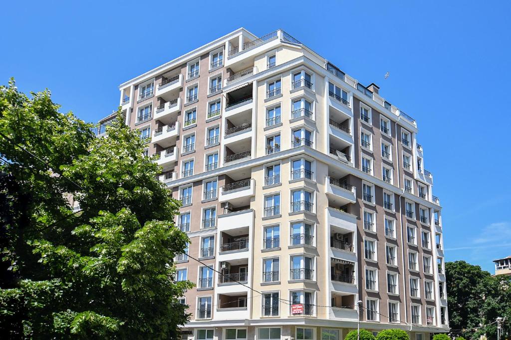 un edificio de apartamentos blanco con balcones y árboles en Chaika 203 en Varna