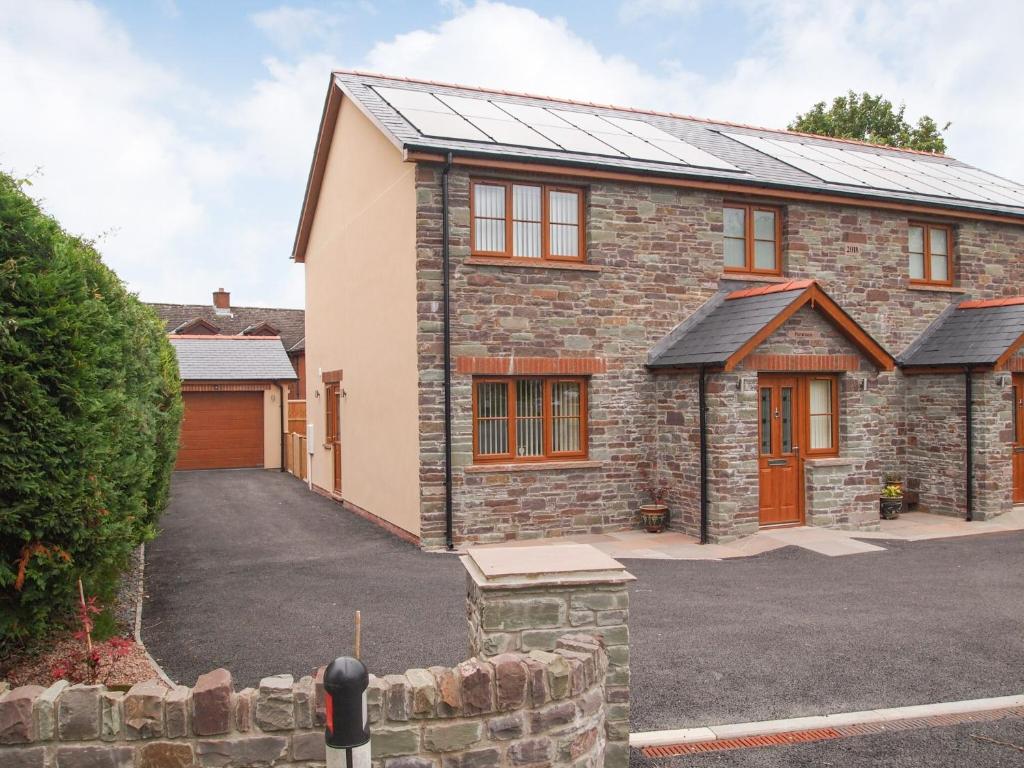 a brick house with a garage and a driveway at Penmaen in Talgarth