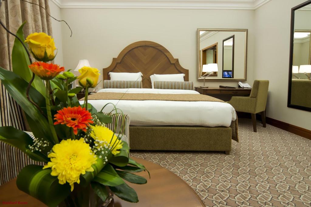 a hotel room with a bed and a table with flowers at Ayla Hotel in Al Ain