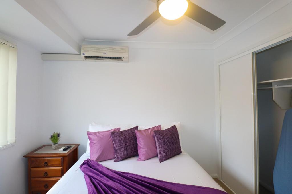 a bedroom with a bed with purple pillows at BLK Stays Guest House Deluxe Units Caboolture South in Caboolture